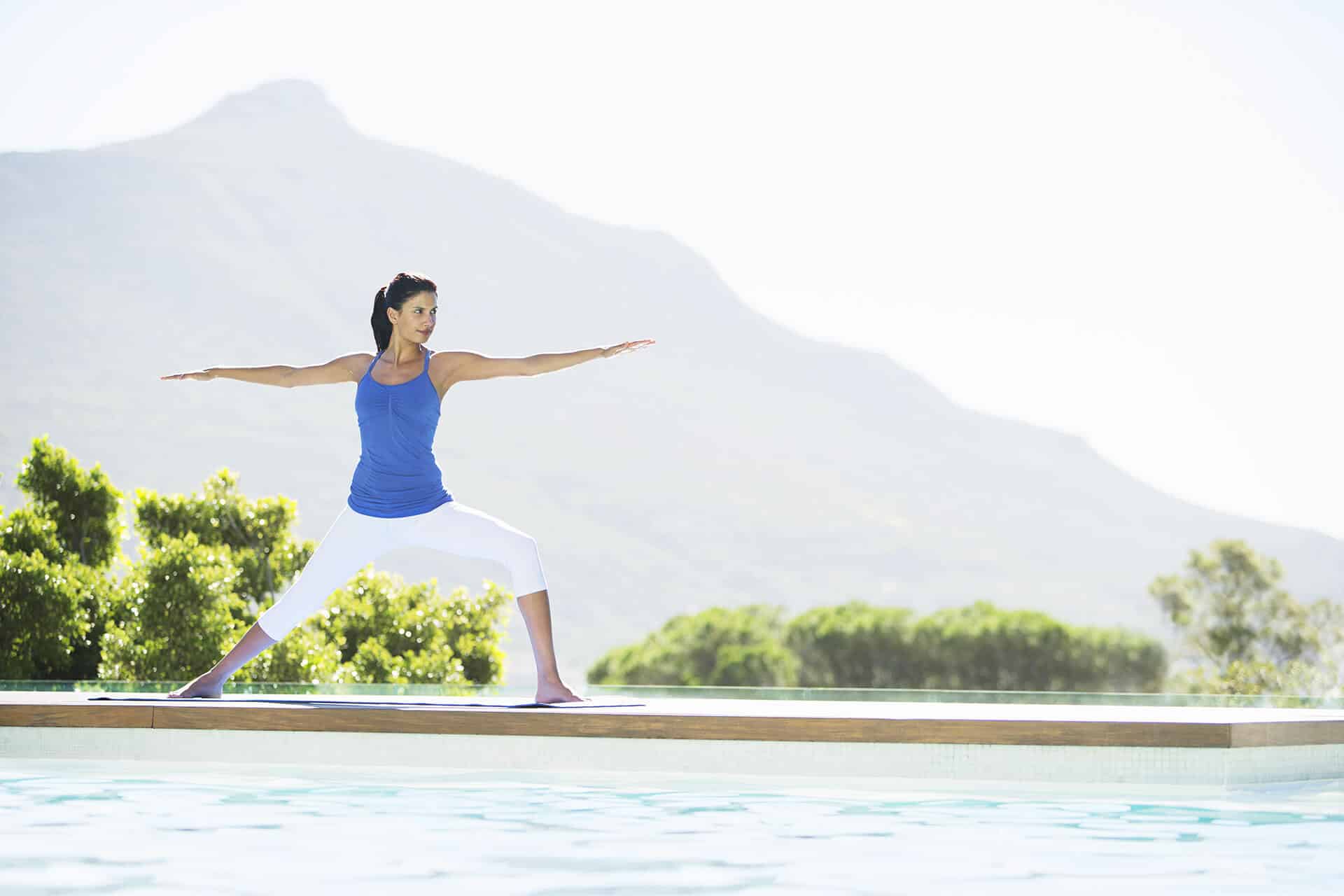 Woman practicing yoga at poolside